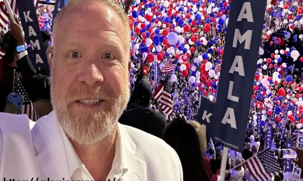 Jesse Dollemore standing with microphone and American flag background, podcast setup in view.